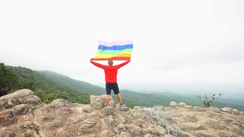 Man waving rainbow flag on mountain top Stock Footage 92248430