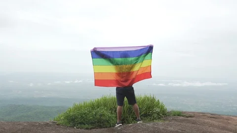 Man waving rainbow flag on mountain top Stock Footage 92248735