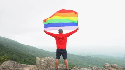 Man waving rainbow flag on mountain top Stock Footage 92249428