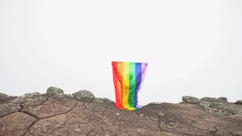 Man waving rainbow flag on mountain top Stock Footage 92250535