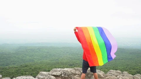 Man waving rainbow flag on mountain top Stock Footage 92250647