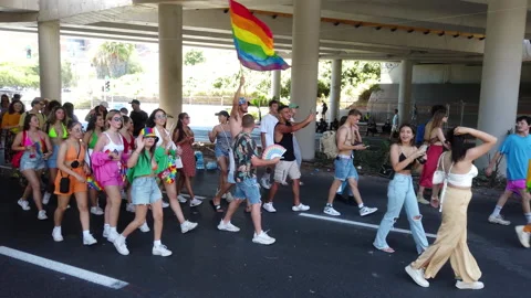 A man waving a rainbow flag walks among people at the pride parade Stock Footage 197340391