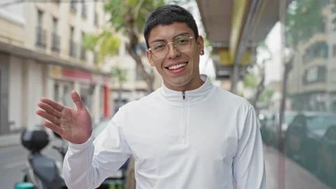 Man waving right hand and smiling, wearing glasses and white zip pullover w.. Stock Footage 337431454
