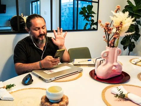 Man Waving While Using Smartphone Remotely Stock-Fotos