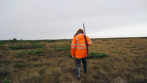 A man with a weapon walks across the field Stock Footage 117350831