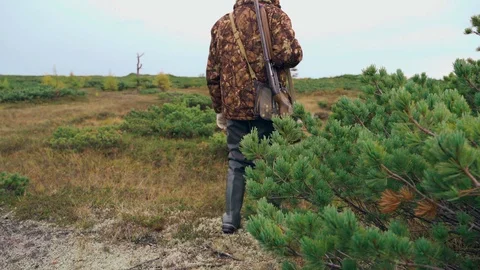 A man with a weapon walks across the field Stock Footage 117351060