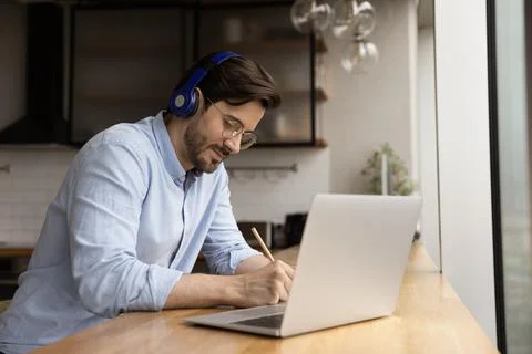 Man wear headphones listens audio course studying at home Stock Photos