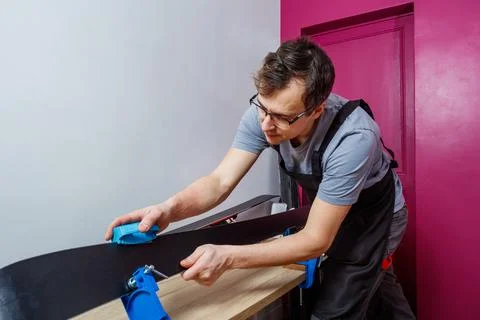 Man wearing apron in a workshop sharp edge of mountain ski Stock Photos