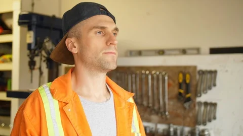 Man Wearing Backwards Hat and Safety Coveralls in Mechanics Shop Stock Footage 90796170