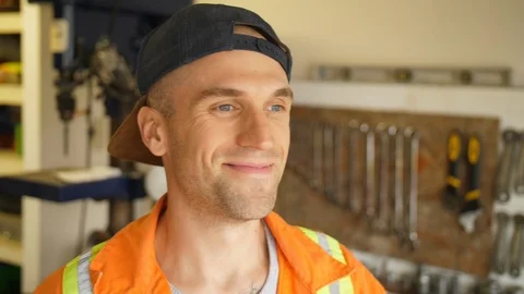 Man Wearing Backwards Hat Safety Coveralls in Mechanics Shop or Garage Smiling Video stock 90799754