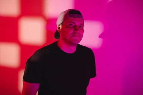 Man wearing baseball cap posing in front of bright neon pink wall. Portrait o Stock Photos