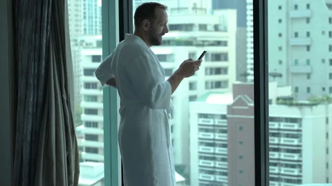 Man wearing bathrobe and texting messages on smartphone Stock Footage 97725667