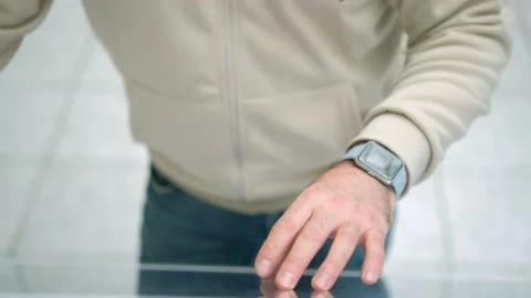 A man wearing a beige jacket and watch is seen interacting with a digital screen Stock Footage 276488944
