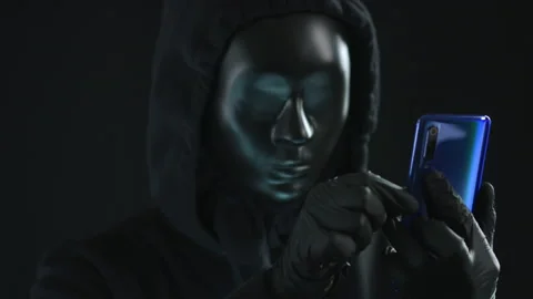 Man wearing black mask pulls TESTING tab from a smartphone. Hacking concept Stock Footage 139577519