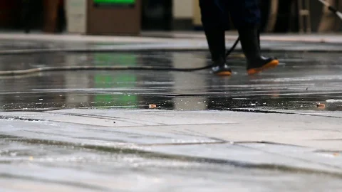 Man wearing black waders cleaning dirty driveway with high pressure water cle Stock Footage 98941518