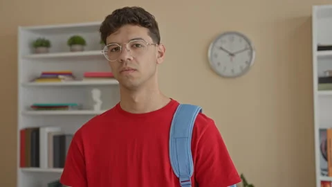 Man wearing a blue backpack stands looking at camera in building study room.. Stock Footage 339196905