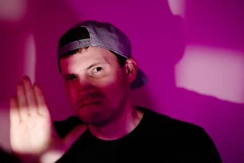 Man wearing cap making stop gesture with hand. Serious guy posing against bri Stock Photos