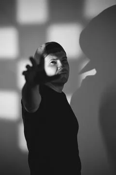Man wearing cap reaching toward camera on dark background. Creative portrai.. Stock Photos
