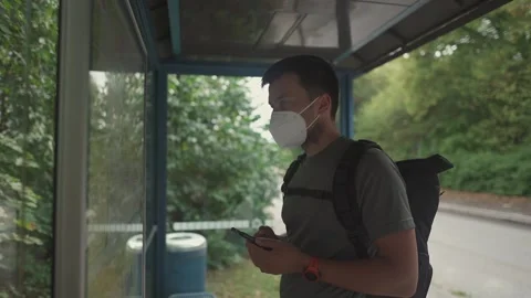 Man wearing a face mask checks bus timetable and route map at a bus stop in Stock Footage 328234748