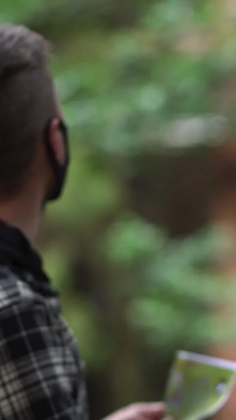 Man wearing face mask lost in the forest looking at a map Stock Footage 290130137
