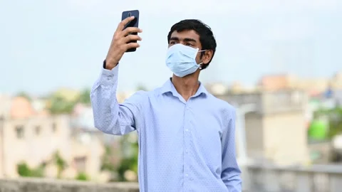 A man wearing face mask is making a video call on smartphone. Stock Footage 133299874