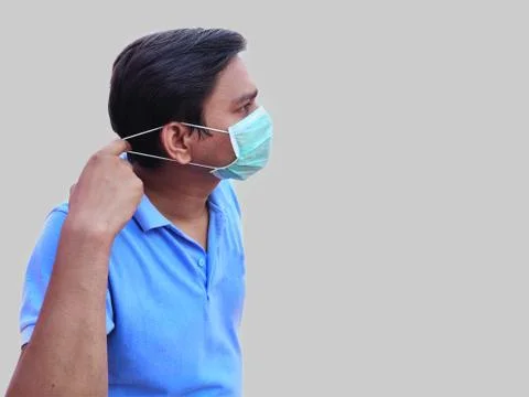 Man wearing Face mask pulling mark strings to place it over Ears Stock Photos