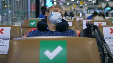 Man wearing face mask sleeping at an airport during global pandemic. Covid-19 Vídeos de archivo 129747844