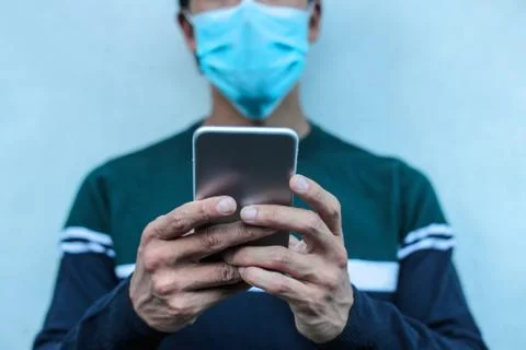Man wearing a face mask, using his smart phone Stock Photos