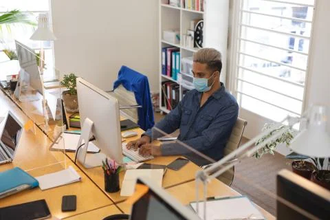 Man wearing face mask using computer at office Stock Photos
