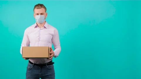 Man wearing face mask while holding a package and standing in the studio. Stock Footage 142008920