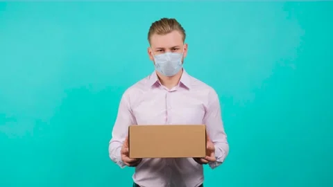 Man wearing face mask while holding a box and standing in the studio. Stock Footage 142009337