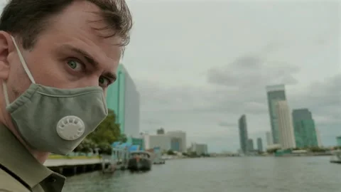 Man wearing face mask while exploring city riverside, fun Stock Footage 256434181