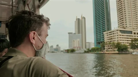 Man wearing face mask while commuting by boat in city Stock Footage 260342031