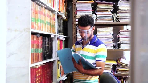 Man wearing face shield busy working in office with lots of legal files Stock Footage 138259381
