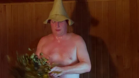 Man wearing felt hat beating body with birch broom inside traditional Russian Stock Footage 342661206