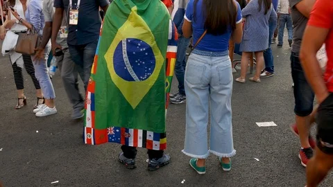 Man wearing a flag of all countries flags standing in street among other fans Video stock 91634172