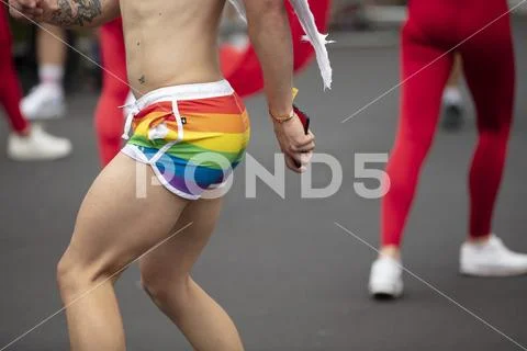 A man wearing gay pride flag shorts dancing in the street at a pride event Stock Photos