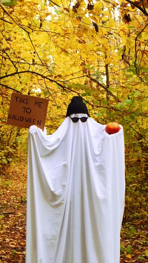 Man wearing ghost costume dancing holding cardboard with text TAKE ME TO Stock Footage 287135746