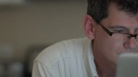 Man wearing glasses looks at computer monitor as camera pans across screen Stock Footage 201501646