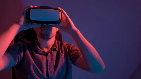A man wearing glasses of virtual reality sits on a chair and moves his hands. 4k Stock Footage 115089344