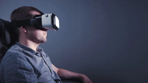 A man wearing glasses of virtual reality is sitting on a chair stretching out Stock Footage 115089503