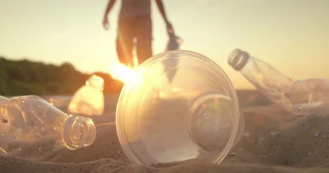 Man wearing gloves picks up empty plastic bottles being cleaned on the beach. Stock Footage 175189107