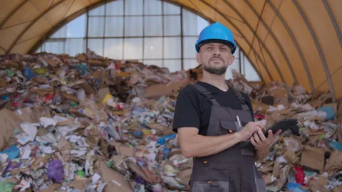 Man wearing hard hat and overalls make calculations on tablet at recycling Video stock 247628995