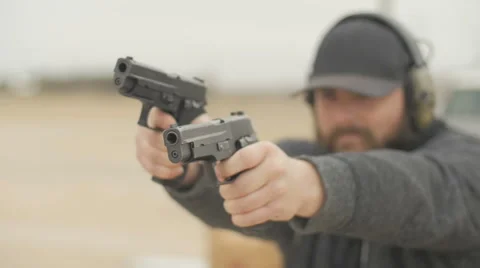 Man Wearing Hat  Firing Two Semi Automatic Handguns Stock Footage 60665330