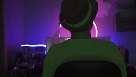 Man wearing hat in neon light room smoking hookah. Stock Footage 130044178