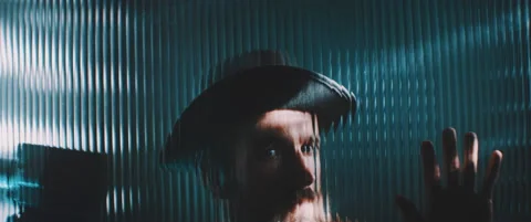 Man wearing hat viewed behind a clear line shaped panel using vintage camera Stock Footage 203570497