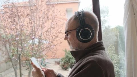 Man Wearing Headphones and Using Smartphone in a Quiet Indoor Setting Video stock 305149677