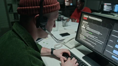 Man Wearing Headset Conducting Phishing Fraud at Computer Screen Stock Footage 346702273