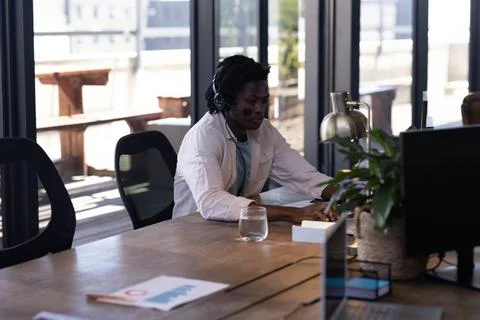 Man wearing headset working on computer in modern office, focusing on tasks Foto stock