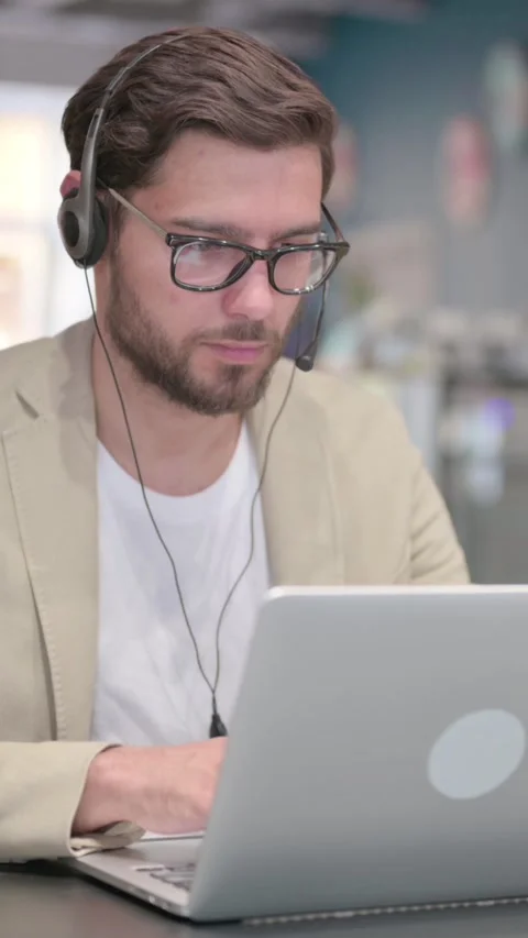 Man Wearing Headset Working on Laptop at Work, Vertical Video Stock Footage 342004942